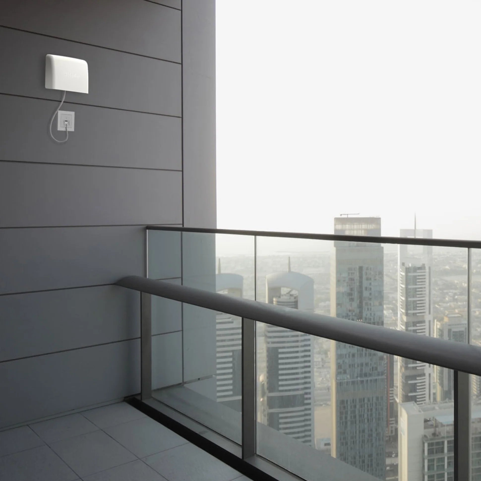 Outdoor air quality monitor installed on a high-rise balcony overlooking city buildings